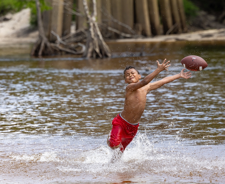 boy playing football in river